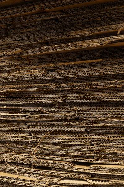 Büyük bir karton yığınının yatay yakın çekimi pürüzlü dokuyu ve sıkıştırılmış katmanları gösterir..