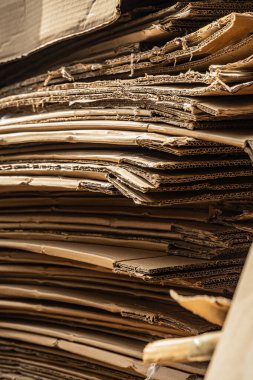 Sıkıştırılmış katmanları ve ham kenarları gösteren büyük bir karton kutu yığınının dikey yakın çekimi.