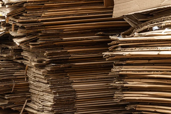 Sıkıştırılmış katmanları ve ham kenarları gösteren büyük bir karton kutu yığınının dikey yakın çekimi.