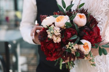 Çift düğün düğün buket peonies, gül ve kırmızı çiçek ve yeşillik elinde tutuyor