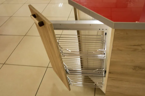 A solution for storing the trash can in the kitchen cupboard under the sink. Corner unit with a pull-out shelf for the trash can.