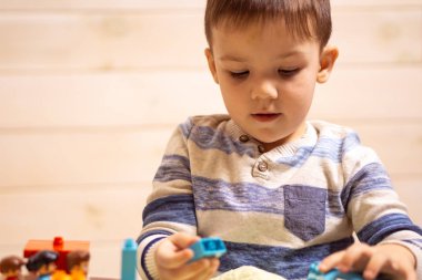 Küçük çocuk evde oyuncak arabayla oynuyor.