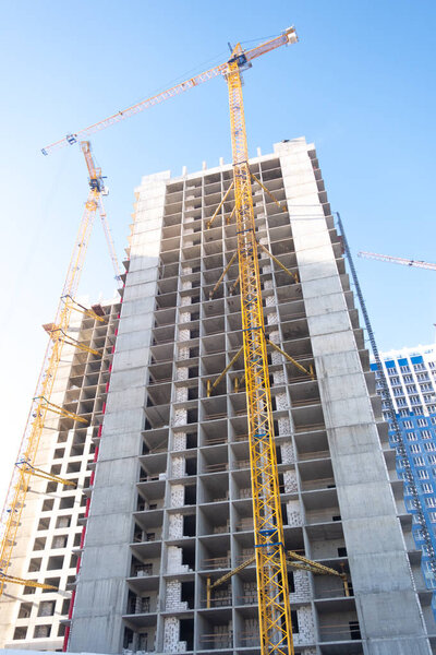 Building a skyscraper with a crane. Construction of high-rise building on the background of blue sky