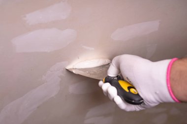 duvarlar, bir spatula ile mavi eldiven bir erkekte tamiri