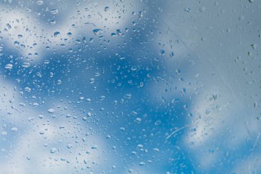 bir pencerede yağmur damlaları bir bulutmavi bir gökyüzü.