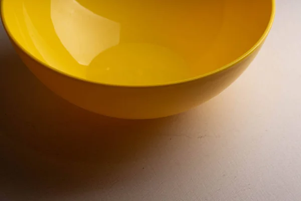 A yellow salad bowl with water drops on the wall is on the table