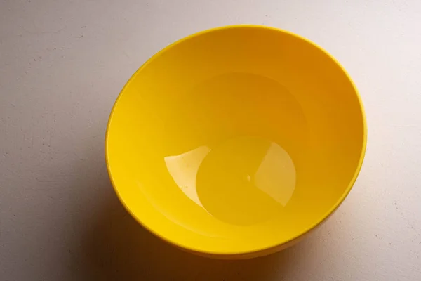A yellow salad bowl with water drops on the wall is on the table