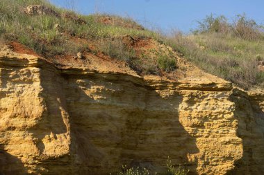Yüksek kumlu uçurum yeşil çim ve mavi gökyüzü ile büyümüş.