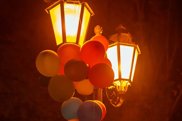 Balões multicoloridos em uma lanterna em um parque da cidade da noite . — Fotografia de Stock
