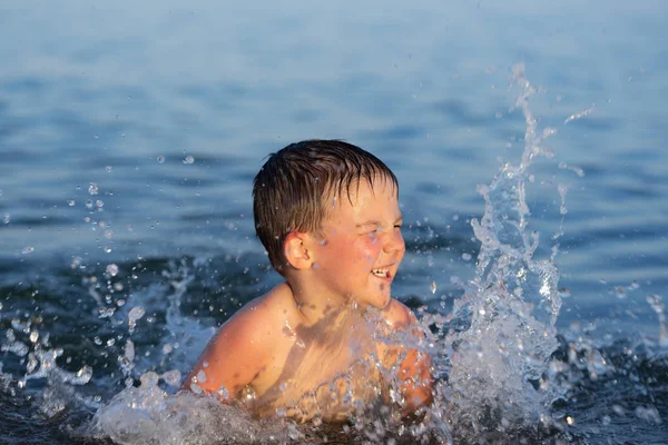 Ein dreijähriger Junge schwimmt mit seinem Bruder bei Sonnenuntergang im Meer. — Stockfoto