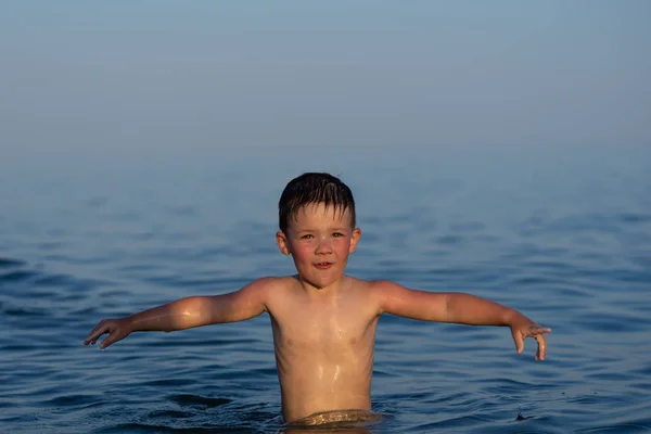 Ein dreijähriger Junge schwimmt mit seinem Bruder bei Sonnenuntergang im Meer. — Stockfoto