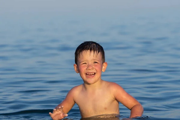 Un niño de tres años está nadando en el mar al atardecer con su hermano . — Foto de Stock