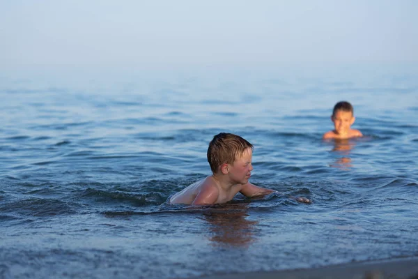 Ένα παιδί τριών ετών κολυμπάει στη θάλασσα το σούρουπο με τον αδερφό του.. — Φωτογραφία Αρχείου