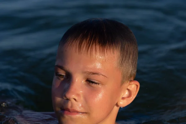 Chłopiec z dziewięciu jest pływanie w morzu o zachodzie słońca. — Zdjęcie stockowe