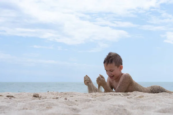 Un niño de 9 años se está bañando y descansando en una playa de arena — Foto de Stock