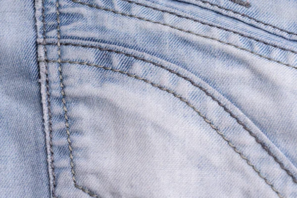 Blue denim. Cotton fabric, jeans. Creative vintage background. Pocket and zipper. The line is of poor quality. Cheap item. — Stock Photo, Image