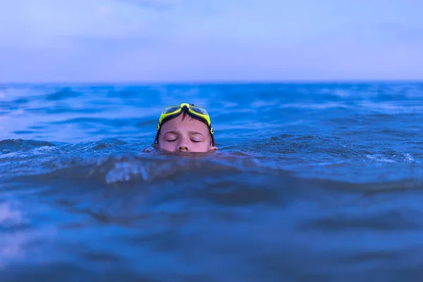 Ένα 10-χρονο αγόρι κολυμπάει στη θάλασσα την αυγή με ποτήρια για κολύμπι — Φωτογραφία Αρχείου