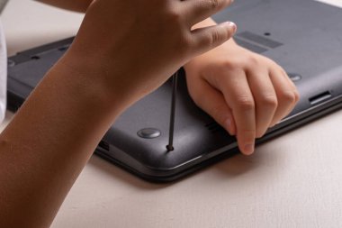 10 yaşında bir çocuk temizlik ve bakım için bir dizüstü bilgisayar sıralama. Seçmeli odak. Tornavidalar, boşaltma silindiri, büyüteç ve sprey temizleyici çerçeveye.