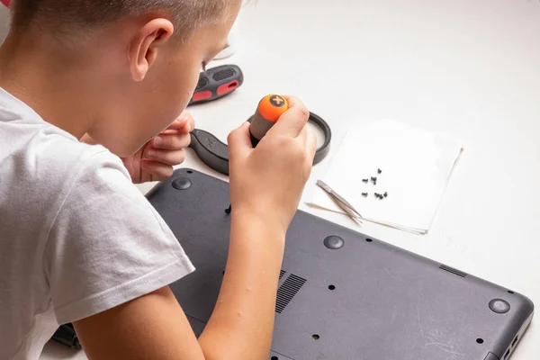 stock image A boy of 10 years old is sorting a laptop for cleaning and maintenance. Selective focus. Screwdrivers, purge cylinder, magnifying glass and spray cleaner in the frame.