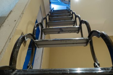 Açıldığında siyah yüksek geri çekilebilir tavan merdivenleri.