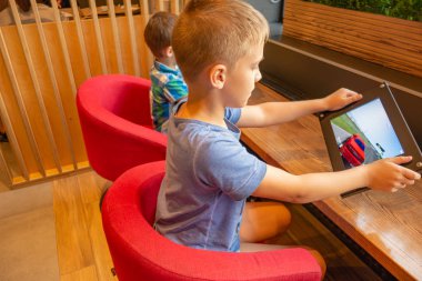 Çocuklar bir şehir kafede tablet üzerinde oynamak.