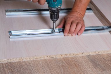 Ahşap yonga mobilyalarını monte eden bir zanaatkarın elleri. Tornavidayla vidaları sıkmak.