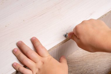 Ahşap yonga mobilyalarını monte eden bir zanaatkarın elleri. Sıkıştırılıyor Vida