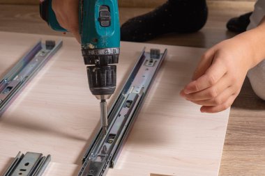 Ahşap yonga mobilyalarını monte eden bir zanaatkarın elleri. Tornavidayla vidaları sıkmak.