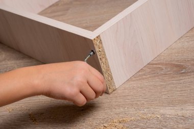 Ahşap yonga mobilyalarını monte eden bir zanaatkarın elleri. Sıkı tut.