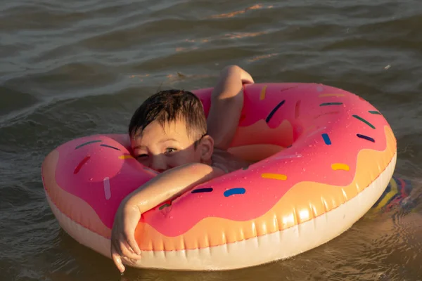 晴れた日にドーナツの形で膨脹可能なリング上の海で陽気な少年5歳の水泳 — ストック写真