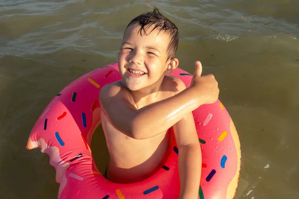 ドーナツ型のインフレータブルサークルと海で5歳の男の子が泳ぐと 次のように表示されます — ストック写真