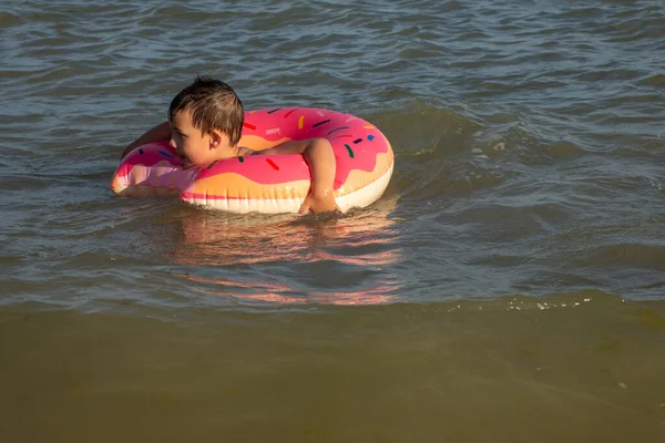 Wesoły Chłopiec Lat Pływa Morzu Nadmuchiwanym Pierścieniu Postaci Pączka Słoneczny — Zdjęcie stockowe