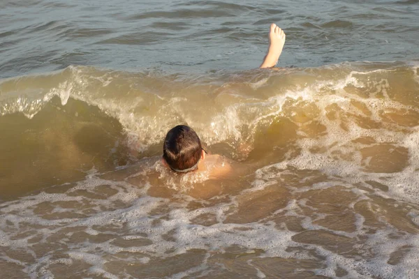 Boy 10 years old enjoys swimming in the coastal waves in the sea