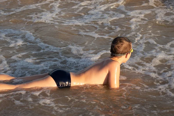 소년은 바닷가의 파도에서 수영하는 즐긴다 — 스톡 사진