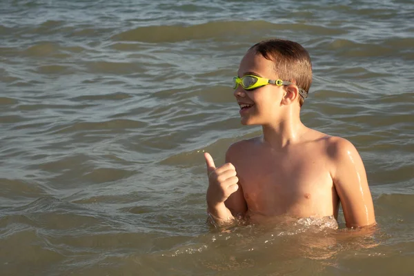 A 10 éves fiú szeret úszni a tengerparti hullámokban. Elégedett az úszás eredményeivel.. — Stock Fotó