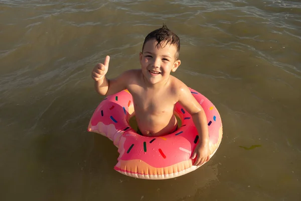 Letni Chłopiec Pływanie Morzu Koło Ratunkowe Pokazuje Podobny — Zdjęcie stockowe