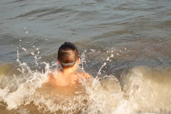 一个10岁的男孩穿着绿色的泳镜 在近岸的海面上游泳 玩得很开心 — 图库照片