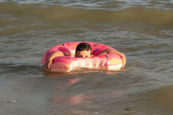 阳光灿烂的日子里 5岁的男孩躺在一只救生圈里沐浴在海里 — 图库照片