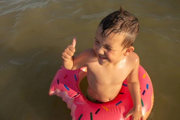 5歳の男の子が救命ボートに乗って海で泳いでいると — ストック写真