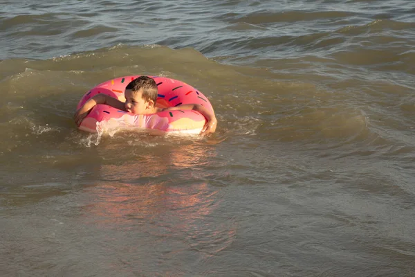 阳光灿烂的日子里 5岁的男孩躺在一只救生圈里沐浴在海里 — 图库照片