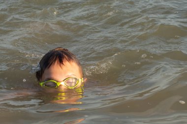 10 yaşında bir çocuk güneşli bir günde denizde yüzer.