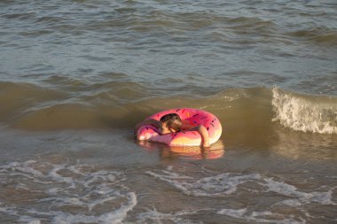 5 yaşındaki bir çocuk güneşli bir günde çörek şeklinde bir hayat yüzüğünde banyo yapar.