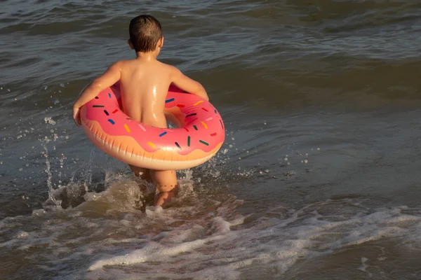 阳光灿烂的一天 一个5岁的男孩在一个甜甜圈状的生活圈里洗澡 — 图库照片