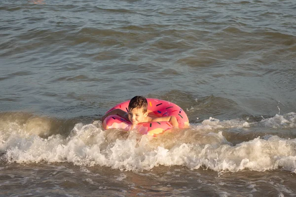 一个5岁的男孩在海岸附近的海里游泳 玩的很开心 他有一个甜甜圈形状的充气圈 — 图库照片