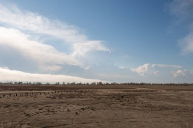 Hafif bir turkuaz gökyüzünün arka planında güzel, şehvetli bulutlar. Arka planda beliren sis. Ufuk ve dar arazi şeridi