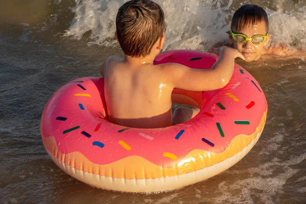 Two brothers 5 and 10 years old swim and have fun in the sea on a clear sunny day