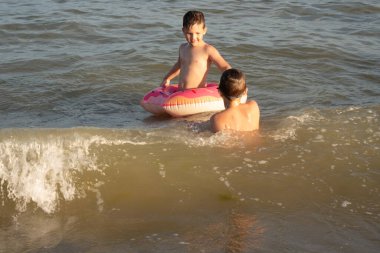 5 ve 10 yaşlarındaki iki kardeş güneşli bir günde denizde yüzer ve eğlenirler.