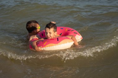 5 ve 10 yaşlarındaki iki kardeş güneşli bir günde denizde yüzer ve eğlenirler.