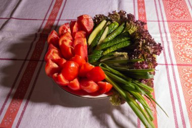 Basit bir yaz yemeği. Domates, salatalık, soğan, masa örtüsü olan bir tabakta marul. Vejetaryen yemeği.