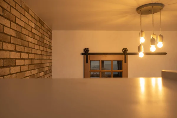 Masa, yaratıcı beton lamba, tuğla duvar ve ahşap sürgülü kapı